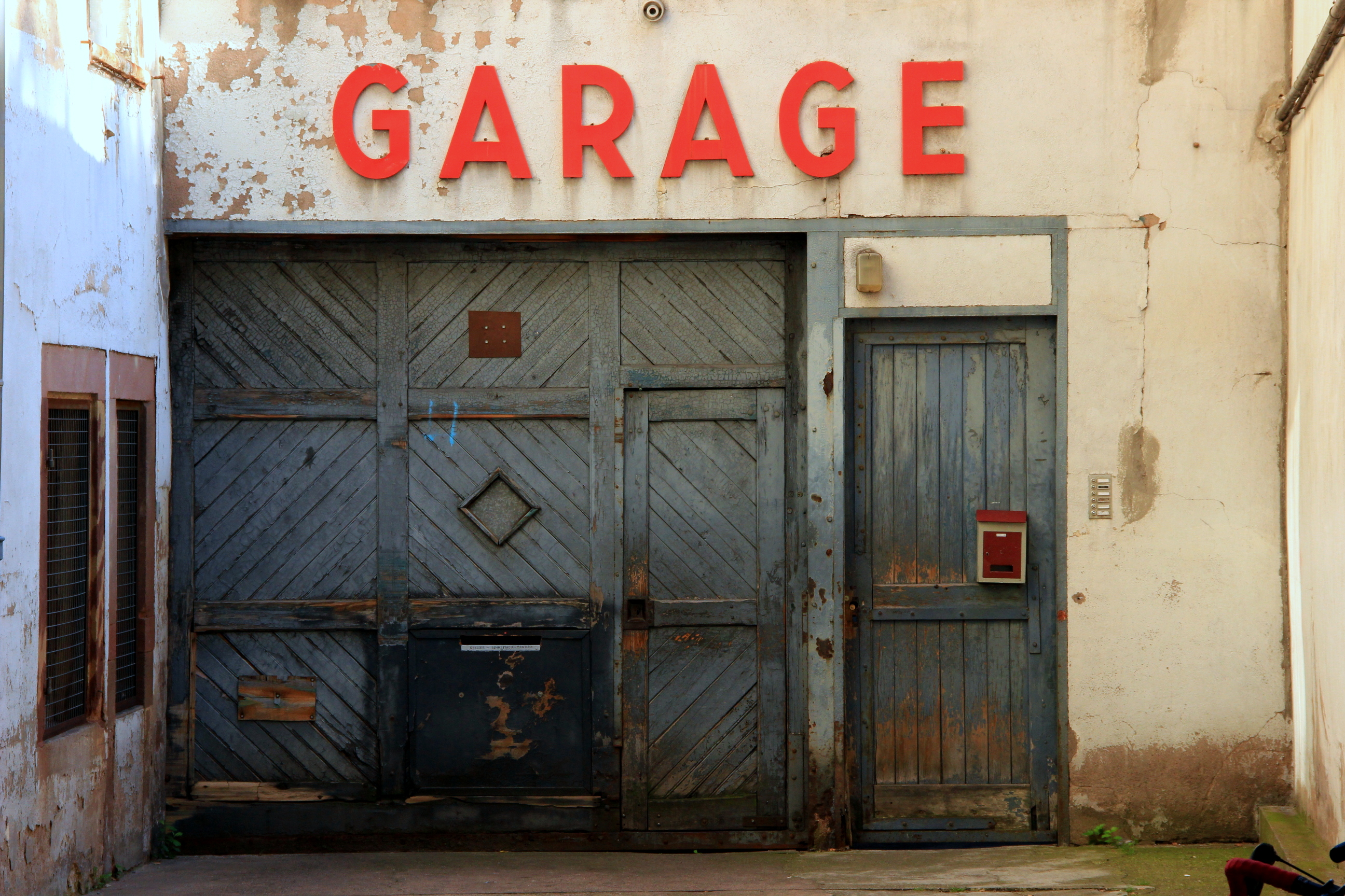 Weathered garage doors beneath large red GARAGE letters