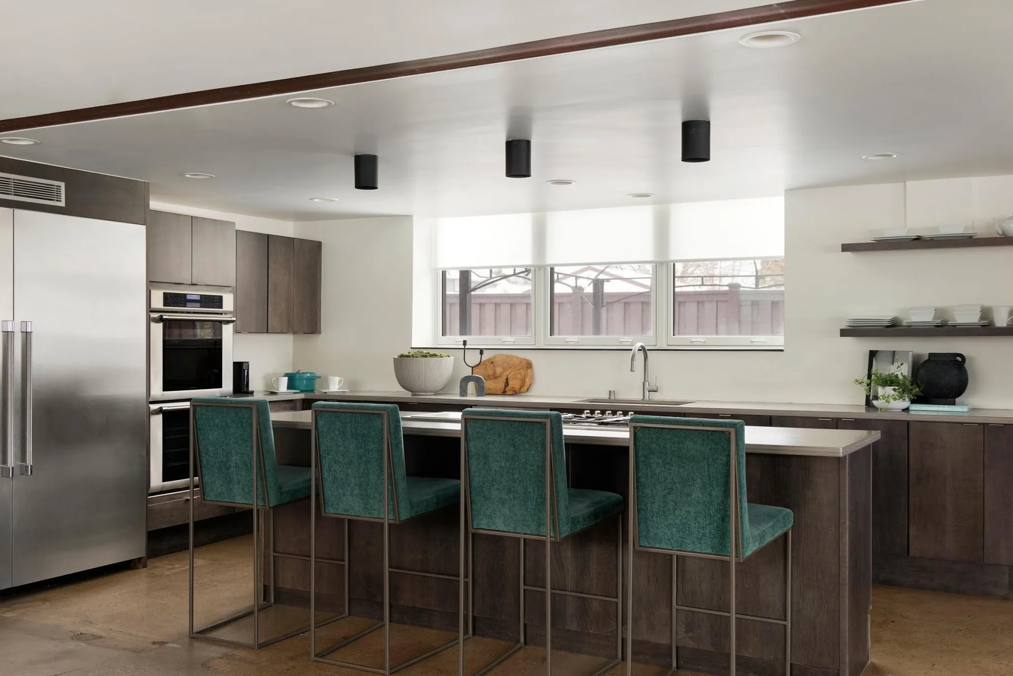 The FIREHOUSE kitchen: a long island with a gas range, double ovens, and open shelving along the back wall.